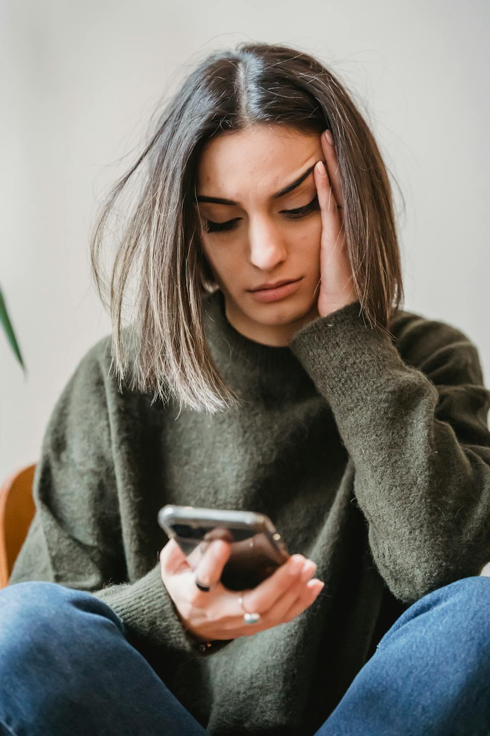 Woman sitting thoughtfully with her phone, looking calm and focused
