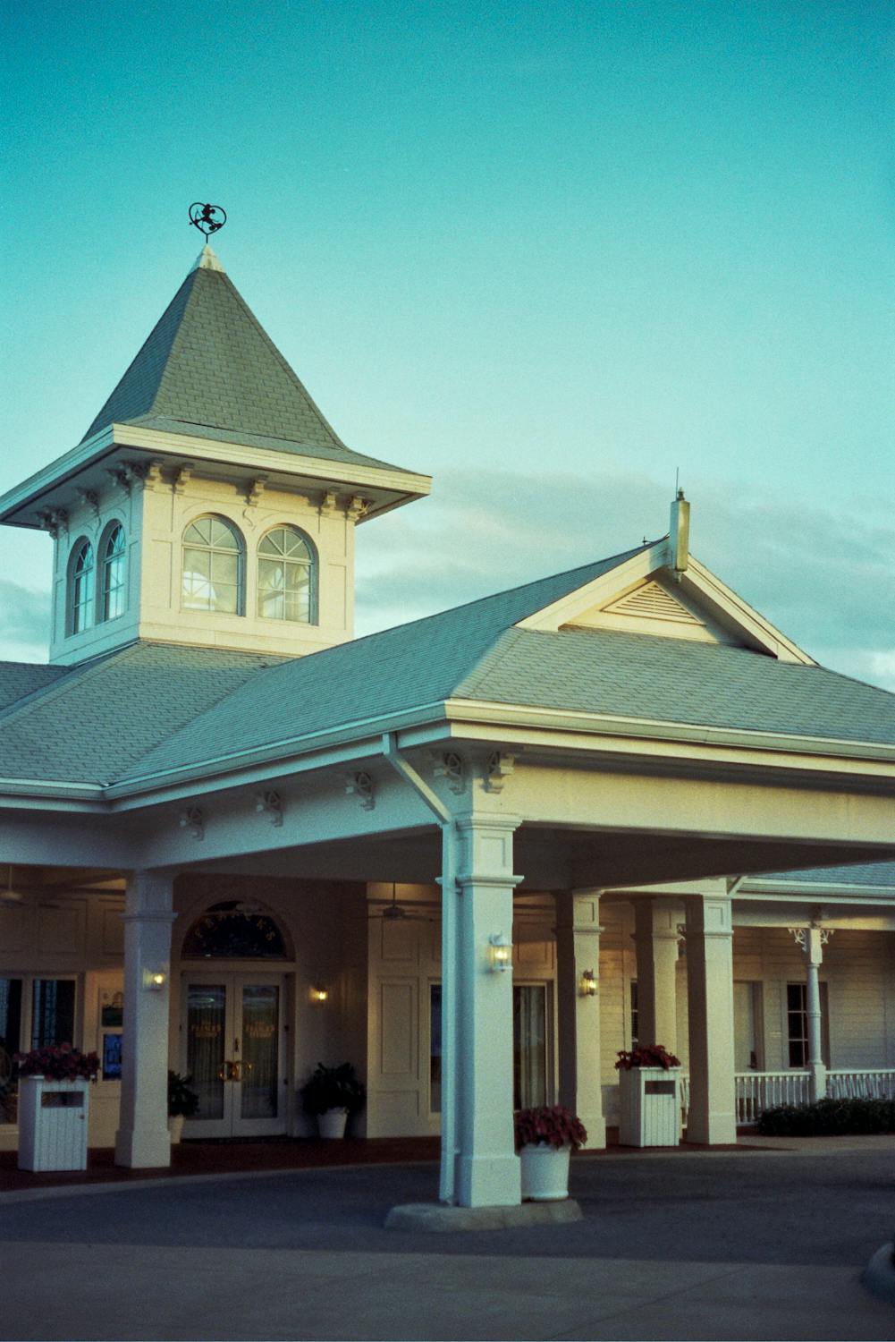 Elegant building facade with a central tower against a clear blue sky, welcoming entrance
