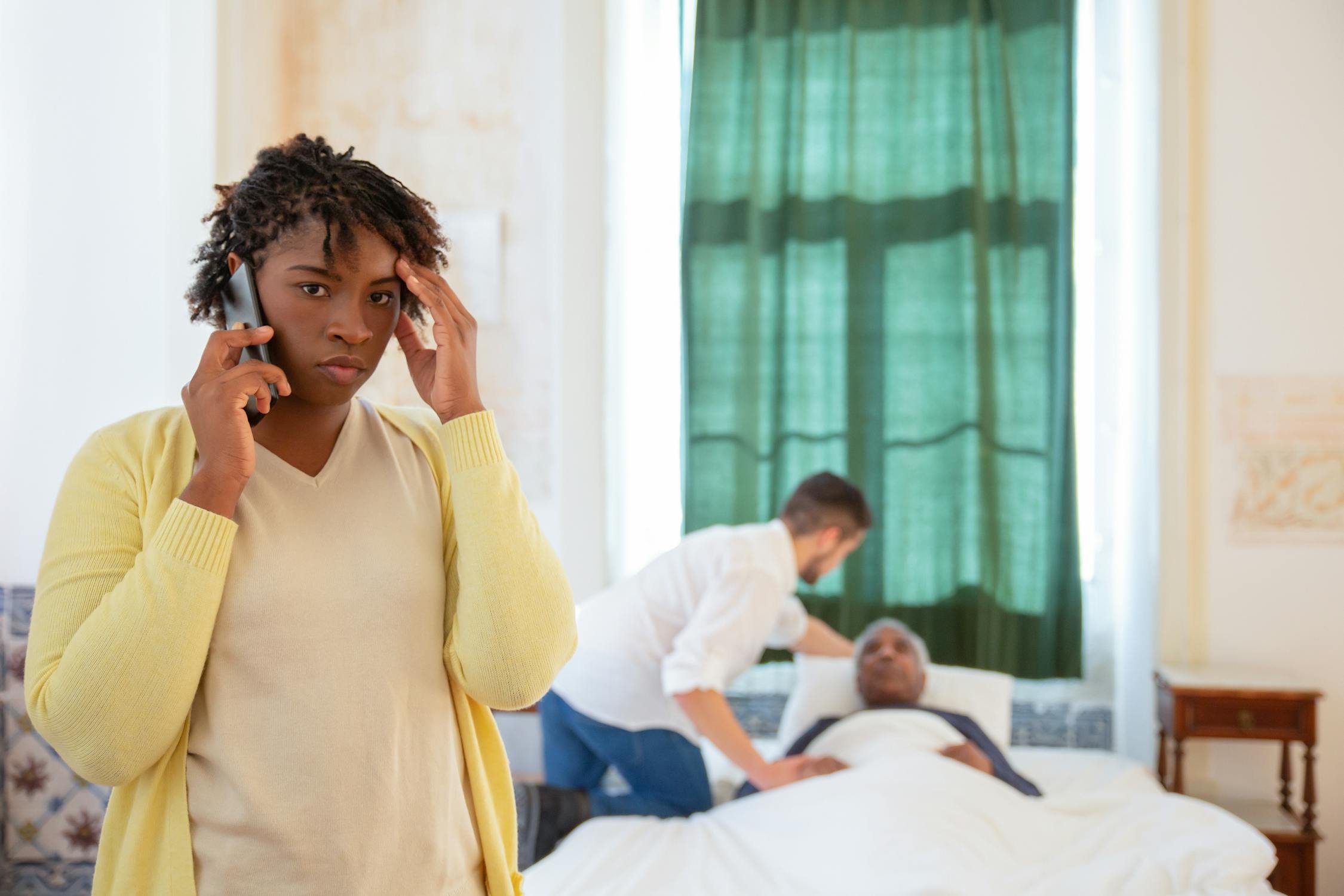 Person on a phone call with a calm, slightly relieved expression, sitting in warm natural light at home