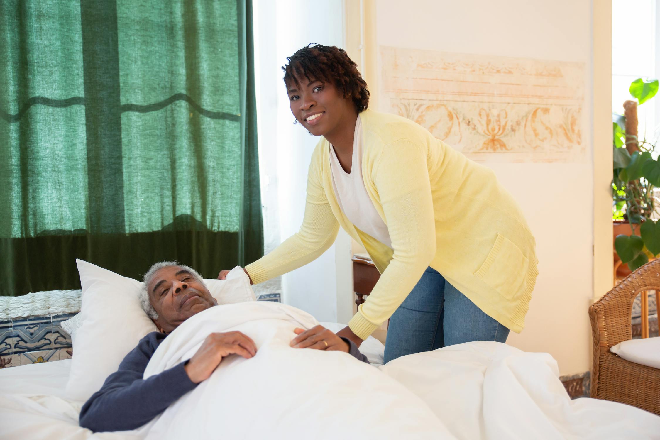 Woman caregiver tending to an elderly man in a bright, warm room
