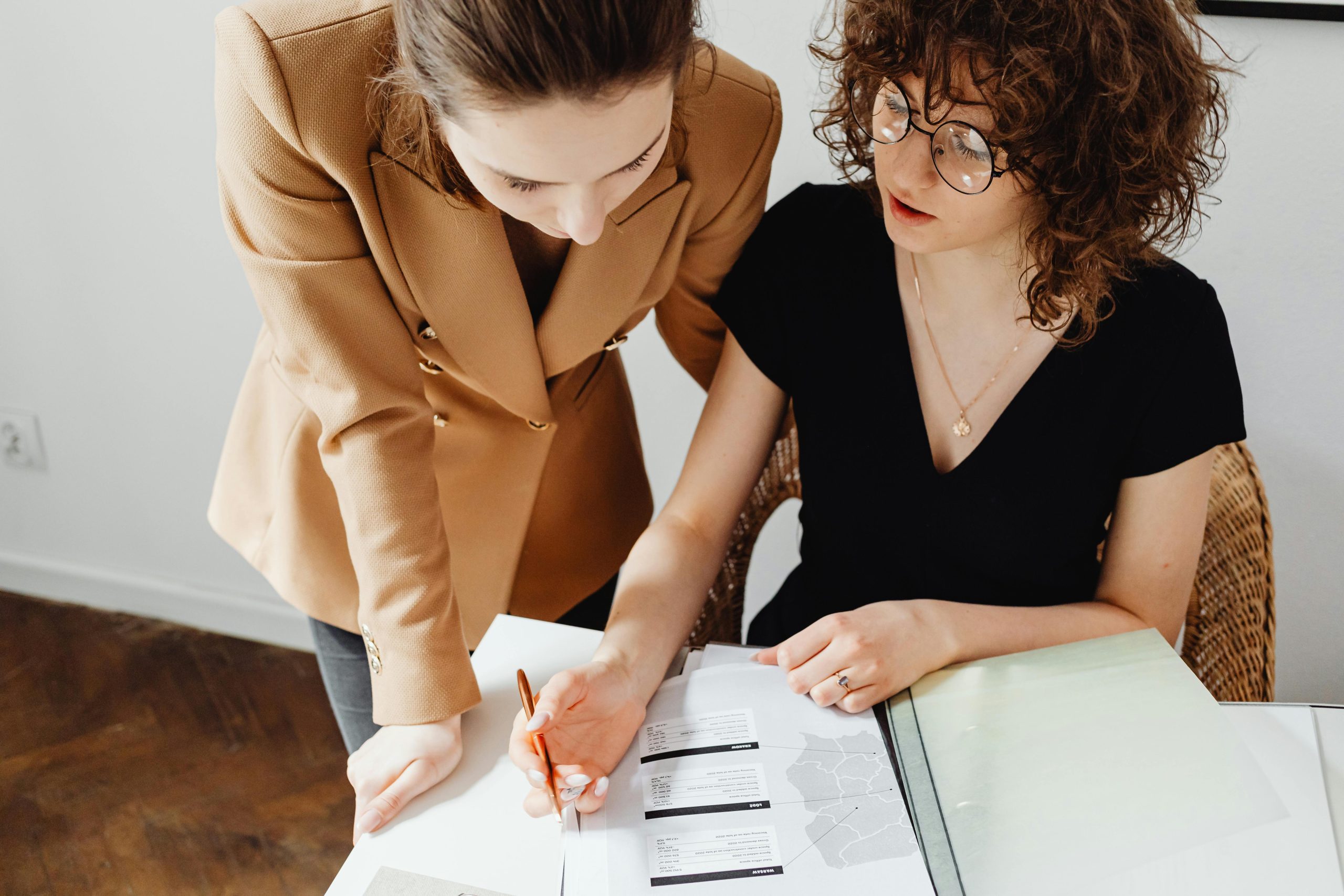 Hospital social worker and adult daughter reviewing discharge paperwork together at a small table in a consultation room