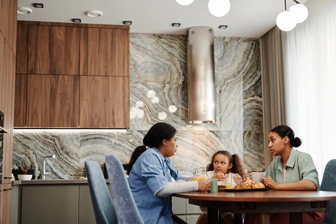 Three generations of women at a kitchen table in open, caring conversation