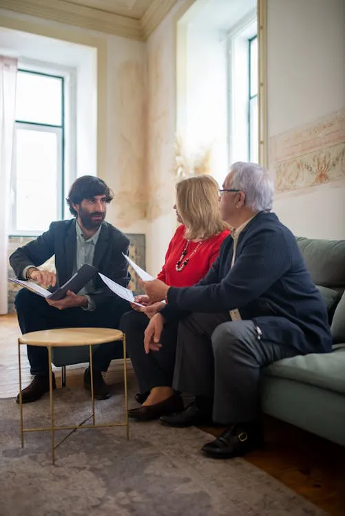 Adult child and aging parents reviewing care documents with a professional advisor at home