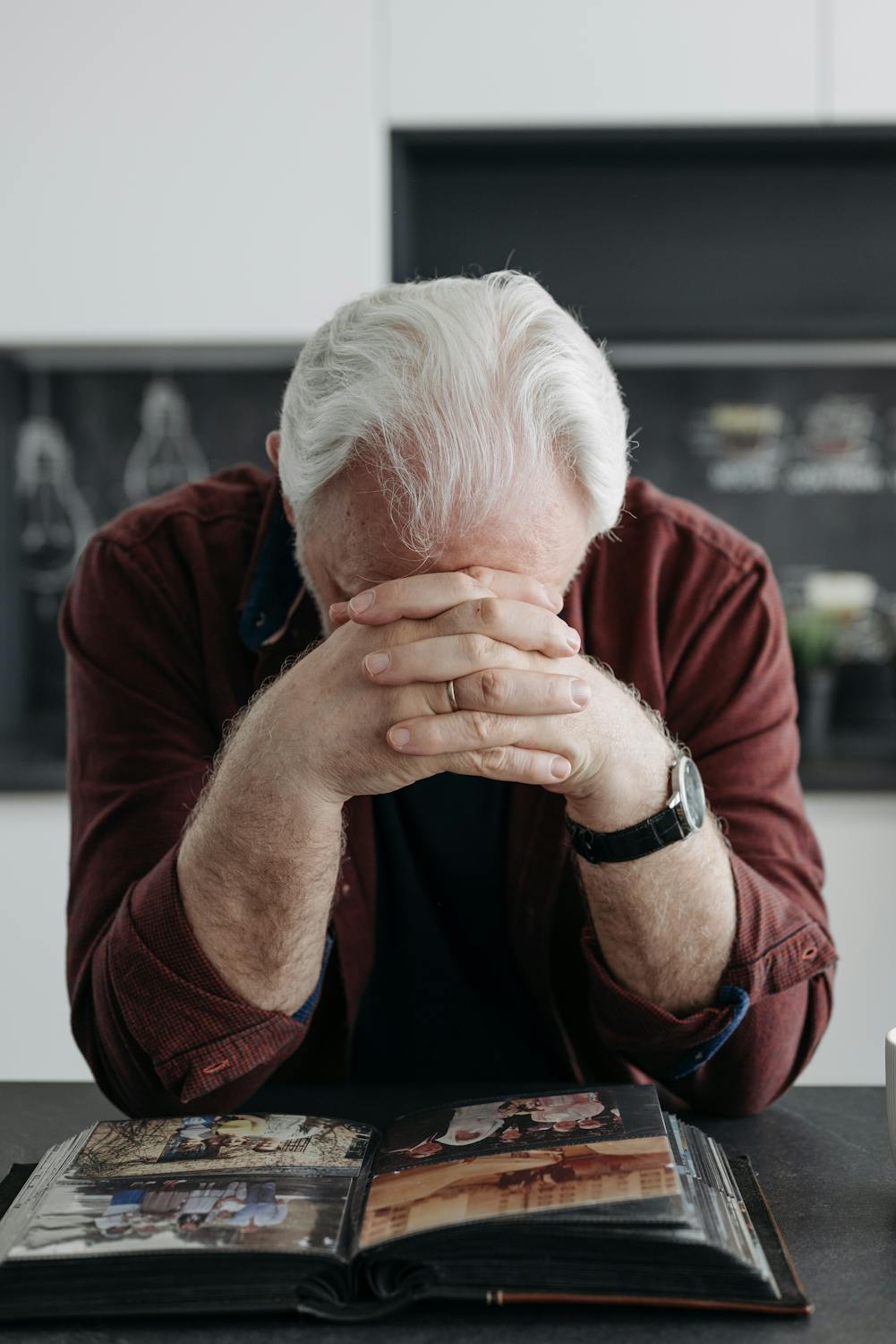 Elderly man with white hair looking through a photo album at home, sharing memories