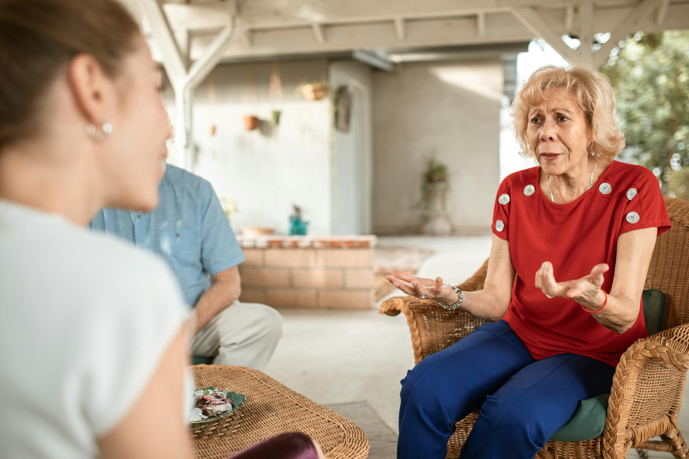 Middle-aged woman having a focused, patient conversation with her elderly mother seated in a sunny outdoor area