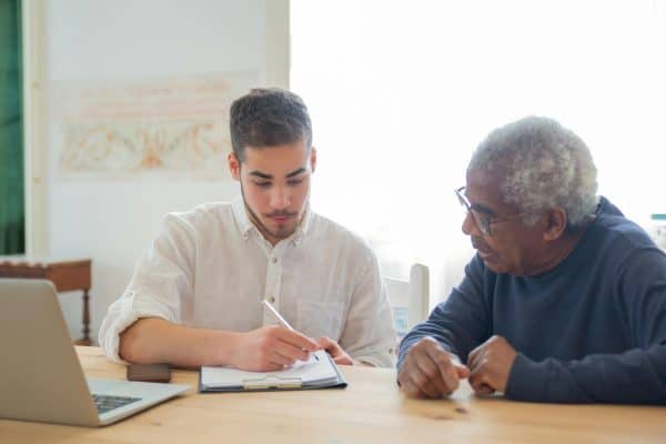 Adult child helping elderly parent with financial paperwork at home