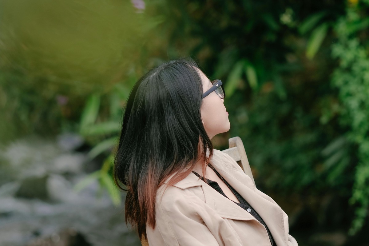 Woman seated outside in a quiet garden, taking a mindful break from caregiving responsibilities