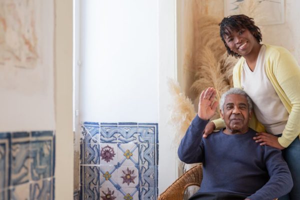 Adult child and aging parent at kitchen table with warm mugs, having a searching conversation about care needs