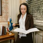 Middle-aged woman sitting in a government office waiting area, holding a folder of documents, looking calm and prepared