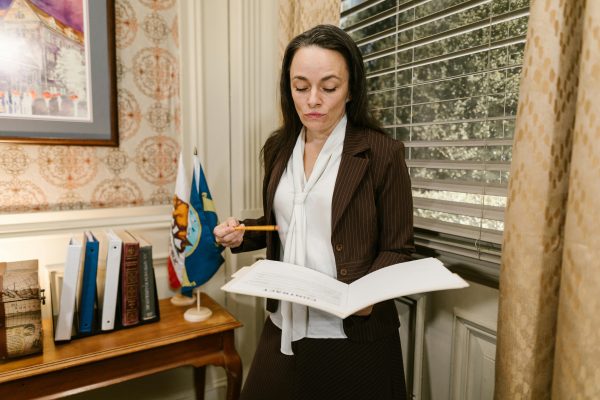 Middle-aged woman sitting in a government office waiting area, holding a folder of documents, looking calm and prepared