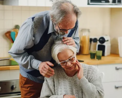 Elderly couple at kitchen table reviewing important papers together with focused care